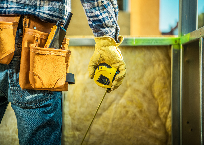 Construction Site Job. Worker with Measurement Tape in Hand and Wearing Tools Belt. Industrial Theme.